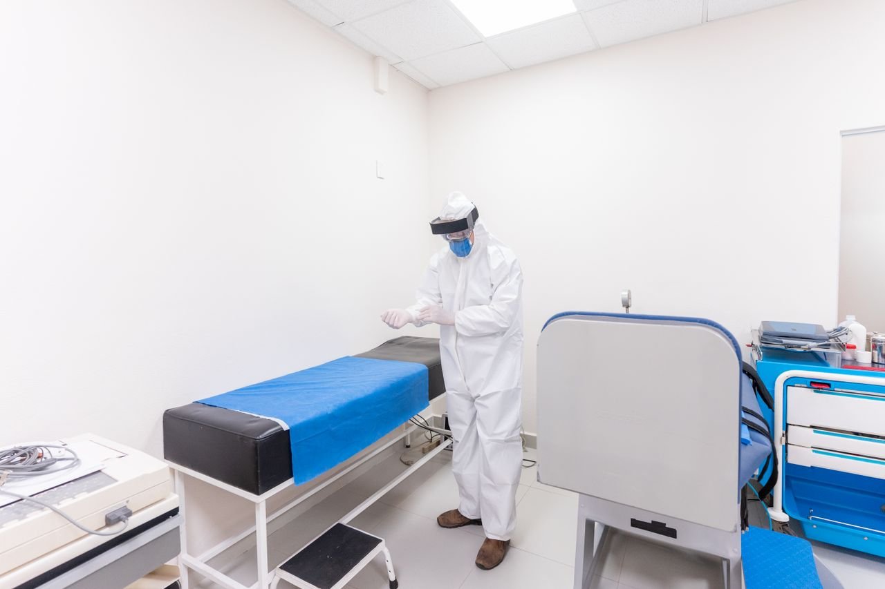 who-we-are A healthcare worker in full PPE readies for work in a well-equipped hospital room.